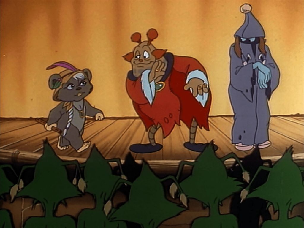 A still from the "Ewoks" cartoon. Latara, a young girl Ewok, is on stage with two members of the Jinda tribe of travelling performers. A group of Duloks sit and watch in the audience.